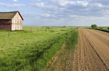 gravel road with barn and green grass surrounding