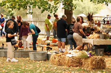 group of people shopping, picking pumpkins, and other items in the fall
