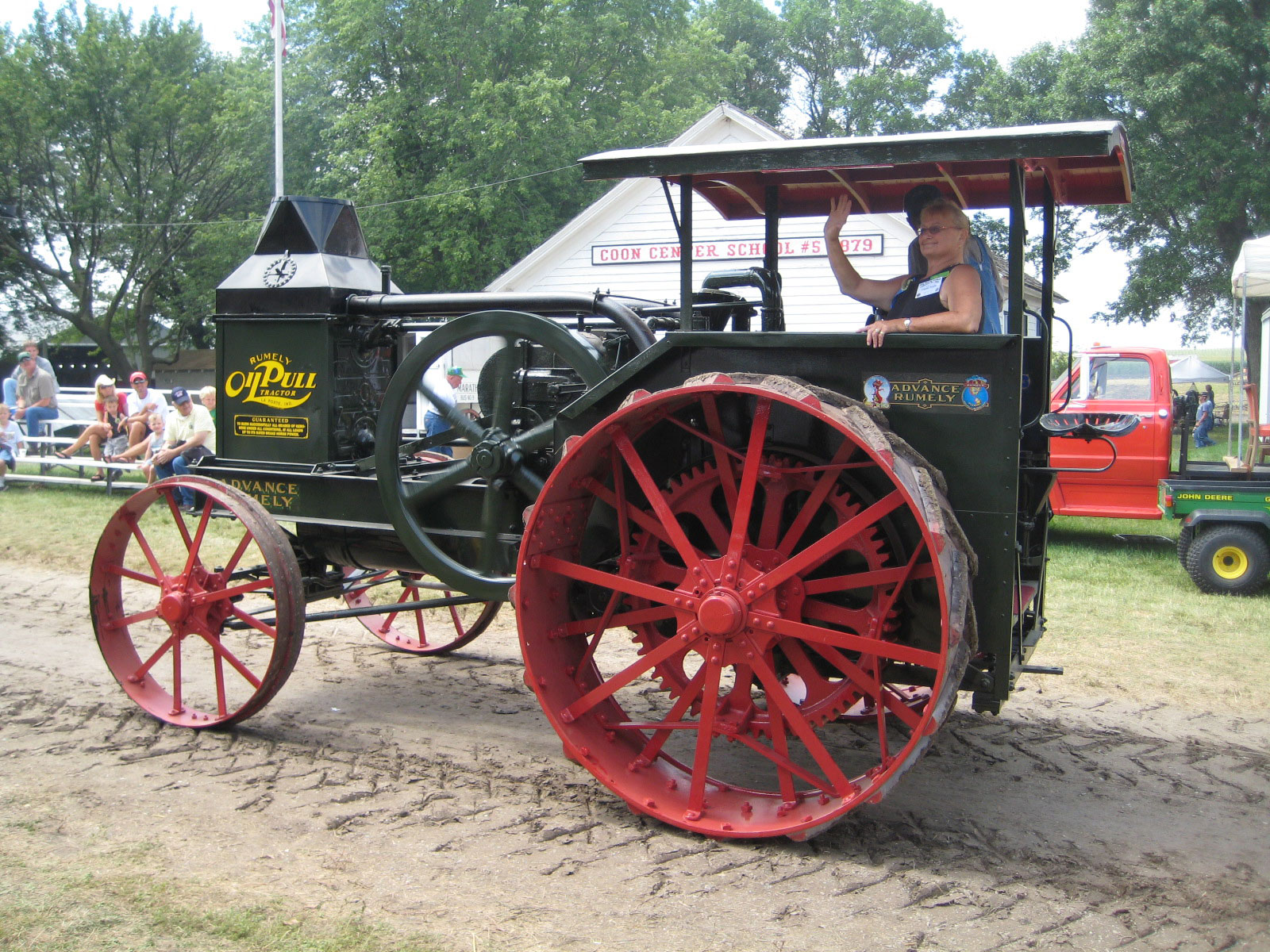 women in old tractor waving as the tractor is going down a dirt road